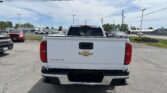 Rear view of a white Chevrolet Colorado pickup in a parking lot, with other cars and power lines overhead.