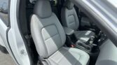 Interior of a white car showing two light-gray leather front seats with headrests, open door side visible