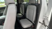 Interior of a gray SUV shown from the rear passenger door, with two back seats and headrests visible; a dealership lot and a sign are seen through the window.