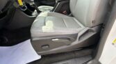 Interior of a car showing the driver and front passenger seats with gray leather upholstery, center console and gear shifter, and dark floor mats; a white sheet on the floor and a yellow key tag hanging near the steering column.
