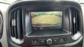 In-dash rearview camera display showing parking lot behind the car with red guide lines for parking.