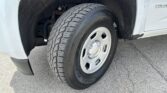 Front wheel of a white pickup truck, showing the tire, wheel cover, and wheel well.