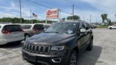 Dark Jeep SUV in the foreground at a car dealership, with an EZ Loan Auto Sales sign and an American flag in the background.