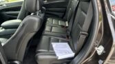 Back seat of a black SUV with leather upholstery; a stack of papers rests on the right rear seat, seat belts visible.