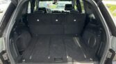 Open SUV tailgate showing a spacious cargo area with the third-row seats upright and a dark carpeted floor, rear bumper visible.