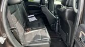 Back seat area of a black SUV with black leather seats and seatbelts, door open to show the interior.
