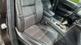 Black leather car interior with front bucket seats, center console, and visible seat belts.