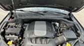 Open car hood showing V8 engine and front battery area with surrounding components visible in the engine bay.