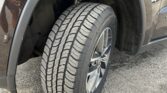 Close-up of a car's front wheel and tire, with the wheel well and fender visible on a dark SUV.