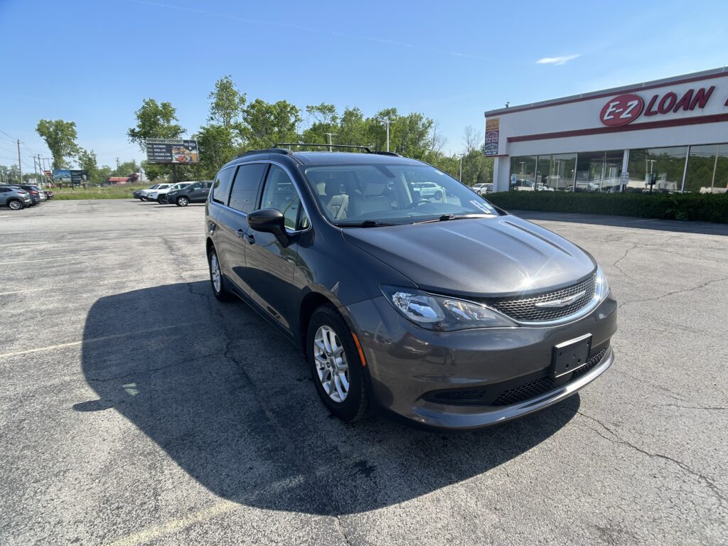Gray minivan in a parking lot near an EZ Loan storefront on a sunny day.