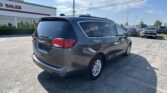 Rear three-quarter view of a dark gray SUV in a dealership lot on a sunny day.
