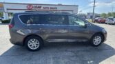 Gray minivan parked in front of an E-Z Loan Auto Sales storefront on a sunny day.