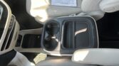 Light gray car interior with a center console cup holder open and a document resting on the passenger seat.