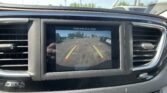 Car dashboard screen showing rearview camera feed with yellow parking lines and a message: 'Check entire surroundings' (informational image)