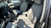 Interior of a beige car with driver and passenger seats, center console, and a sheet of paper on the passenger seat; other vehicles visible outside the windows.