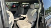 Beige leather SUV interior with front and second-row seats, open rear door, and a parking lot visible outside the window.