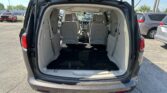 Open tailgate of a gray minivan revealing beige interior and two rows of seats in a parking lot