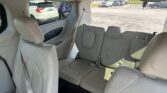 Interior of a light gray SUV showing two rows of beige leather seats and a parked lot visible through the windows.