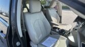 Open driver-side door reveals a light gray leather SUV interior; papers sit on the front passenger seat.