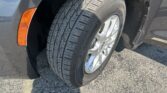 Close-up of a car tire on a silver wheel, showing tread pattern and partial orange fender marker