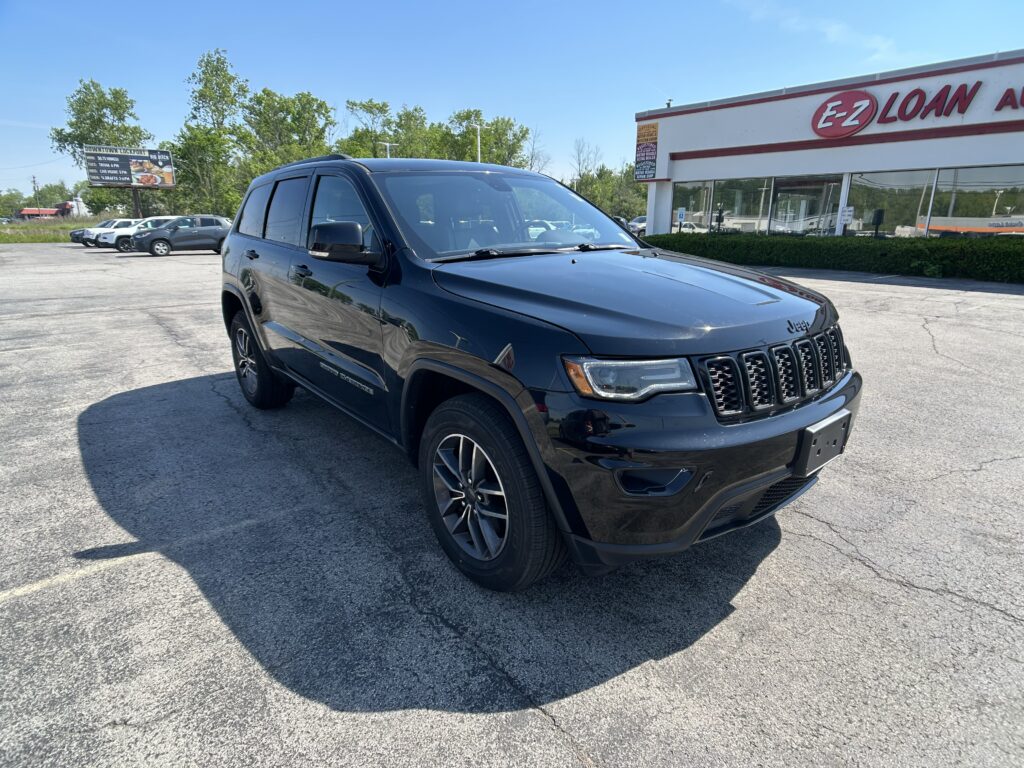 Black Jeep Grand Cherokee SUV parked in a lot in front of an E-Z Loan storefront on a sunny day.