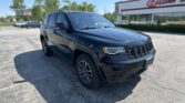 Black Jeep Grand Cherokee SUV parked in a lot in front of an E-Z Loan storefront on a sunny day.