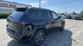 Black SUV parked in a dealership lot with the 'AUTO SALES' sign visible in the background.