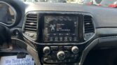 Car dashboard with a touchscreen displaying radio, tuning to 96.9 Classic Rock, in a parking lot view outside the windshield.