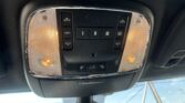 Overhead car console with two small map lights lit and central control panel featuring auto buttons and window shade switches (inside a vehicle)
