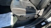 Front passenger seat in a black leather car interior, with a red seat belt buckle visible near the center console area and Jeep door sill.