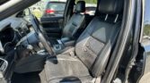 Interior of a black SUV showing front seats, steering wheel, and center console with a sunroof above.