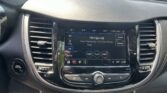 Close-up of a car dashboard with an in-dash touchscreen displaying FM radio and controls around it, plus the engine start/stop button to the left.