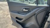 Interior of a car door panel with window controls and chrome handle, view of a parking lot through the window