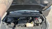 Open car hood revealing engine bay with Chevrolet EcoTec engine cover and visible battery, coolant reservoir, and hoses.