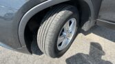 Close-up of a black vehicle's front wheel and tire, with the fender and wheel arch visible.