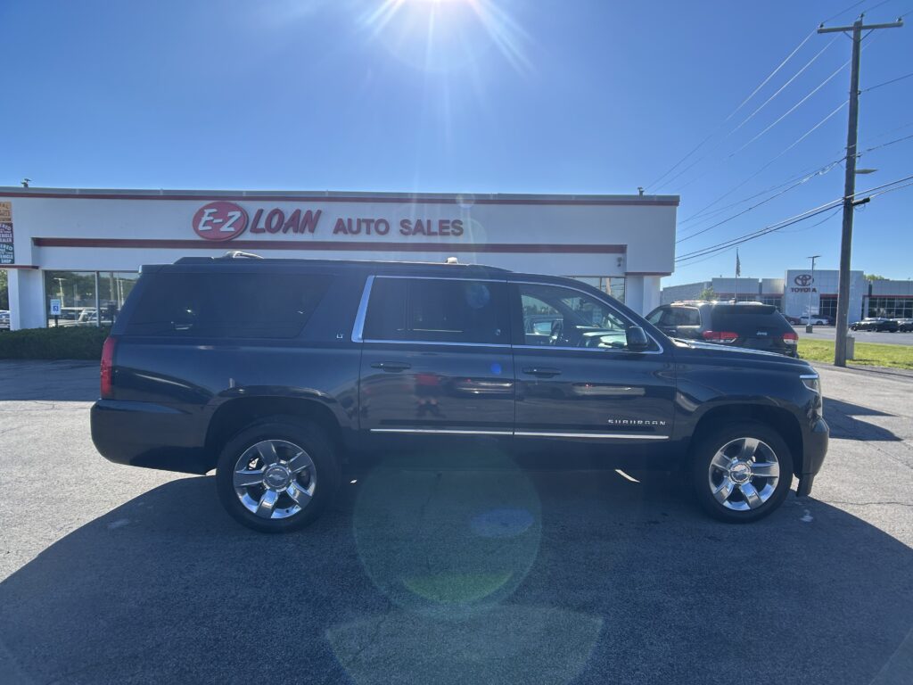 Dark SUV parked in front of an E-Z Loan Auto Sales storefront on a sunny day.