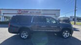 Dark SUV parked in front of an E-Z Loan Auto Sales storefront on a sunny day.