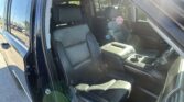 Dark leather SUV interior with front seats and center console, door open on a sunny day, lens flare in the foreground