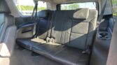 Rear row of black leather seats in an SUV with visible seat belts and cup holder in the center