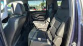 Rear passenger cabin of a dark leather SUV with front seats visible and large side windows; sunny outdoor scene outside the vehicle.