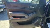 interior of a car door panel with a chrome door handle, window/lock controls, and a Bose speaker; parking lot visible outside.