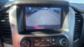 Car’s rearview camera display showing a parking lot with parked cars on both sides and guiding red and orange lines for reversing safety