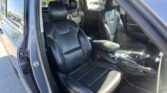 Interior of a car with black leather seats, front passenger seat and center console visible via an open door.