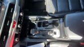 Center console and gear shifter area inside a dark leather-car interior with climate controls visible to the left of the shifter