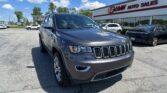 Front-left corner view of a gray Jeep SUV parked at a car dealership lot in front of the EZ Loan Auto Sales storefront.