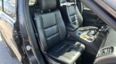 Front interior of a black leather SUV with the driver and front passenger seats and center console visible, door open.