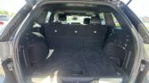 Open SUV trunk with third-row seats upright and a spacious cargo area behind them