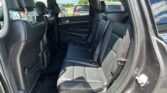Back seat of a black leather SUV interior with headrests and seat belts visible outside the windows.