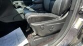 Inside a car: black leather front seats, center console, gear shift, with papers on the floor by the door edge.