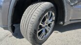 Close-up of a dark SUV's front left wheel and tire in the wheel well.